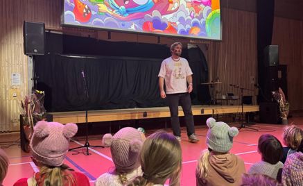 En person som står foran en gruppe mennesker som sitter på gulvet