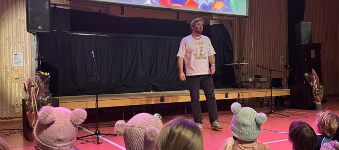 En person som står foran en gruppe mennesker som sitter på gulvet